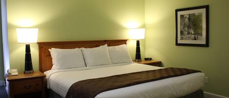 A hotel room with a large bed, two bedside lamps, a nightstand, and a framed picture on the wall.