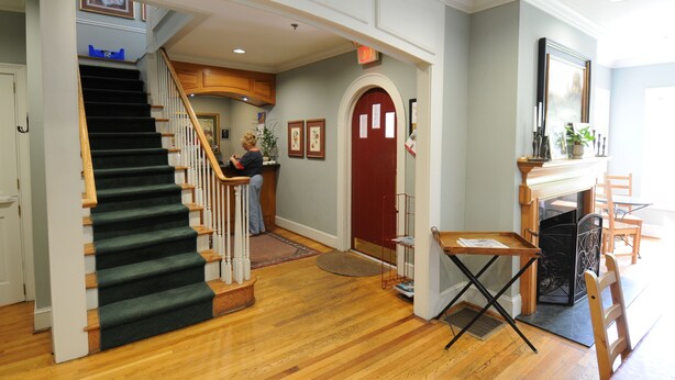 A staircase with a dark carpet, wooden railings, and a red door at the top. - The University Inn at Emory (Atlanta)