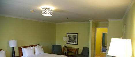 Une chambre d’hôtel avec deux lits, un bureau, une chaise, une lampe et un tableau au mur.