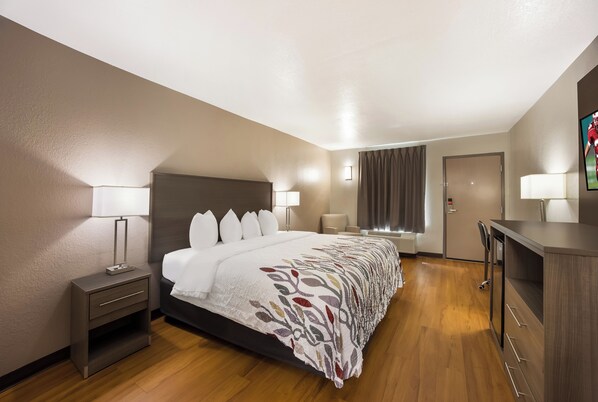 Una habitación de hotel con cama, mesitas de noche, escritorio y silla.