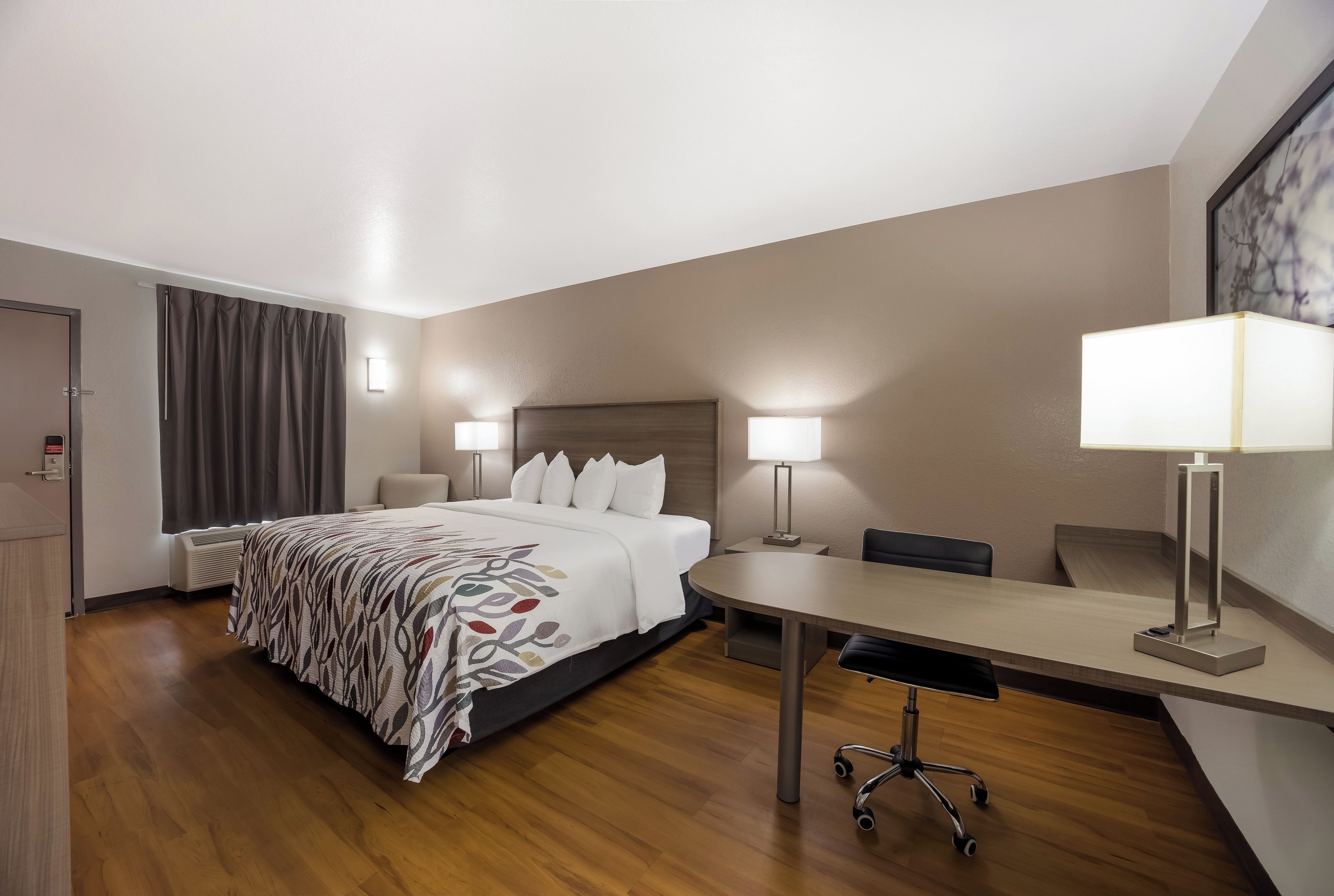 Una habitación de hotel con cama, mesitas de noche, escritorio y una silla.