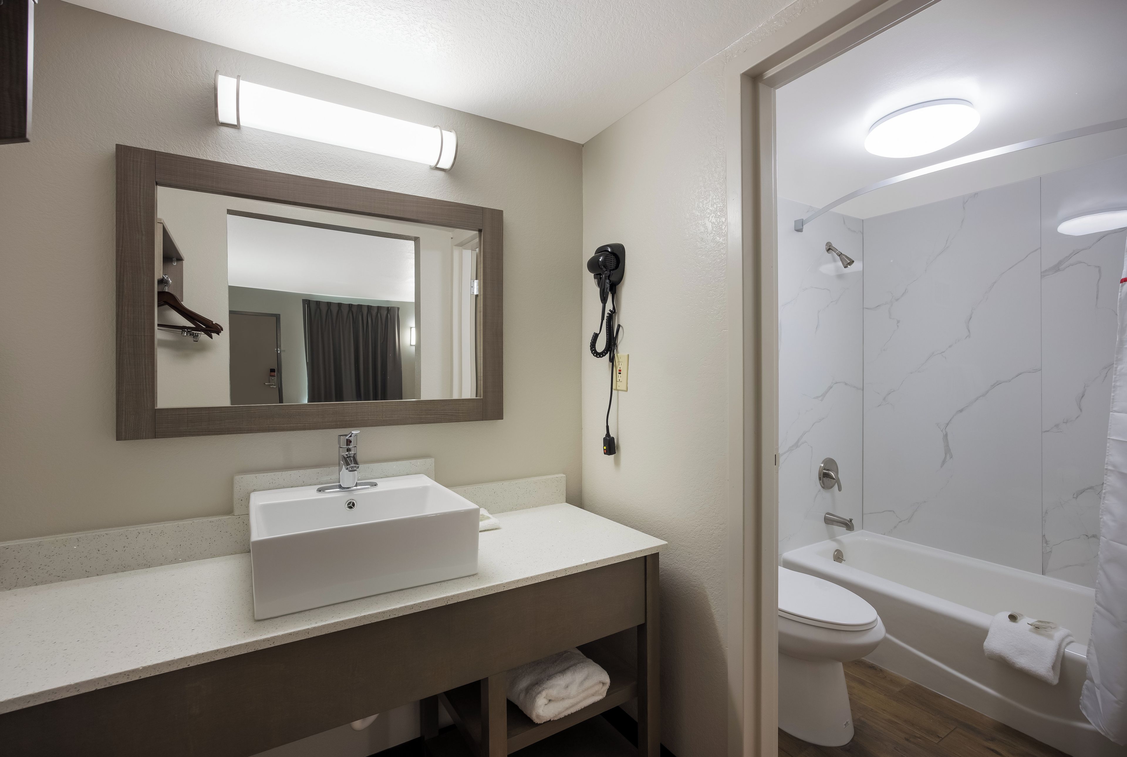 A bathroom with a sink, mirror, and a shower area.