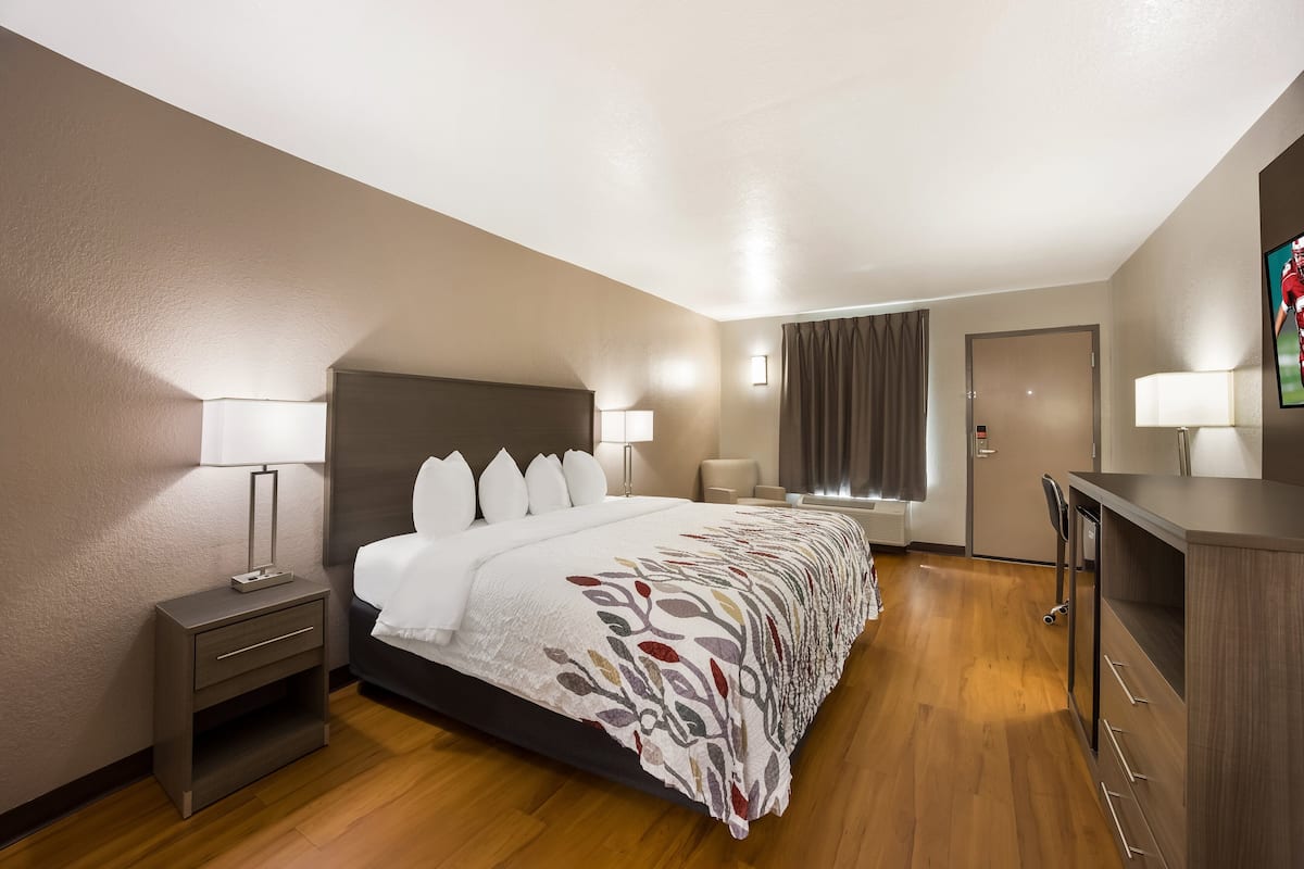 A hotel room with a large bed, bedside tables, a desk, and a chair.