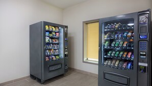 Two vending machines in a room with a window.