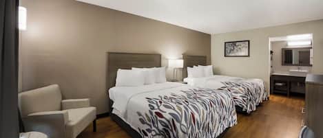 Una habitación de hotel con dos camas, un escritorio, una silla y un baño.