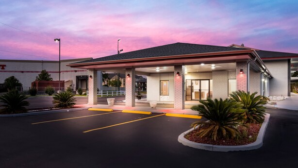 Un motel con un'area di parcheggio coperta, facciata in mattoni e ingresso curato.