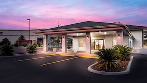 A hotel with a covered entrance, a parking lot, and a clear sky.