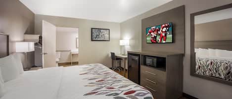 A hotel room with a bed, a desk, a television, and a mirror.