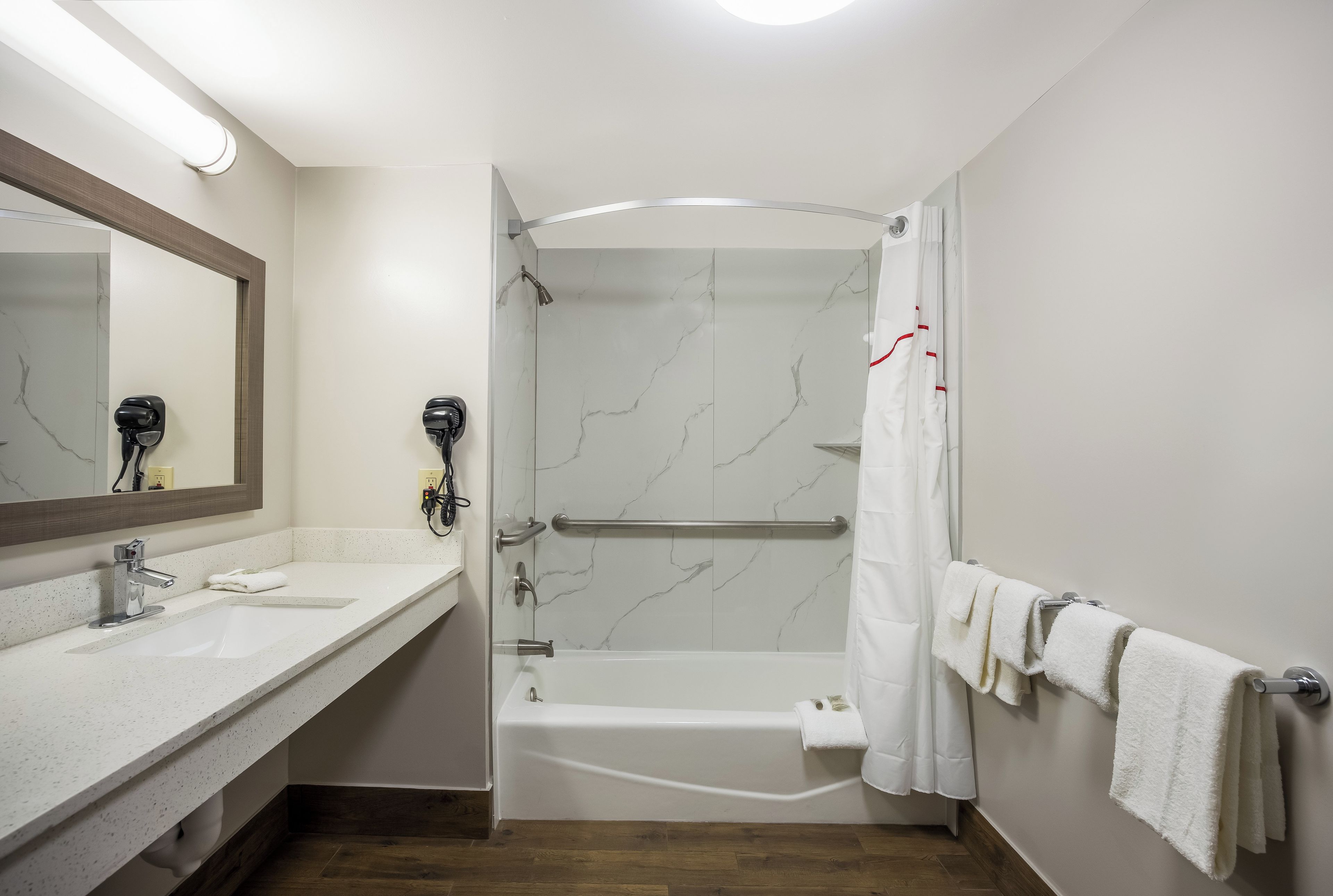 A bathroom with a shower, a bathtub, a sink, a mirror, and a towel rack.