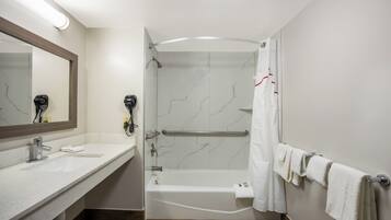 A bathroom with a shower, a bathtub, a sink, a mirror, and a towel rack.