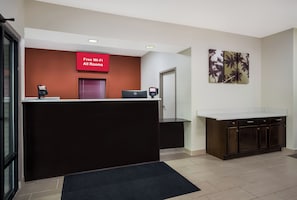 Zona de recepción de un hotel, con un letrero rojo que indica Wi-Fi gratuito, un mostrador de recepción, una computadora y un cuadro grande en la pared.