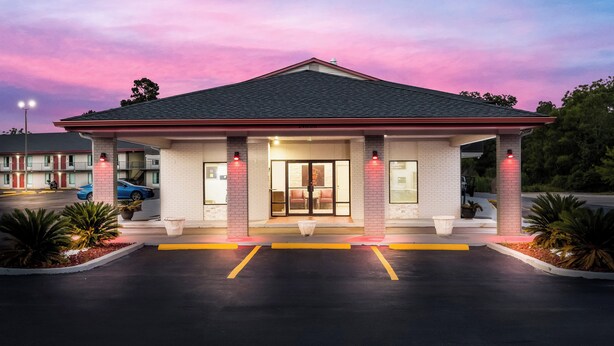 A motel with a single-story structure, a flat roof, and a parking lot with marked spaces. - Red Roof Inn & Suites Thomasville (Thomasville)
