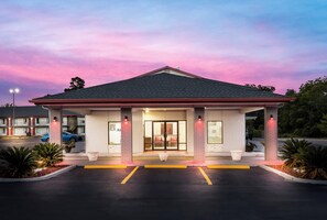 Un motel con fachada de ladrillo, un acceso cubierto y un estacionamiento.