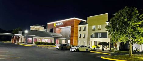 Un hotel con un letrero que dice 'QUINTA', un estacionamiento y un árbol.