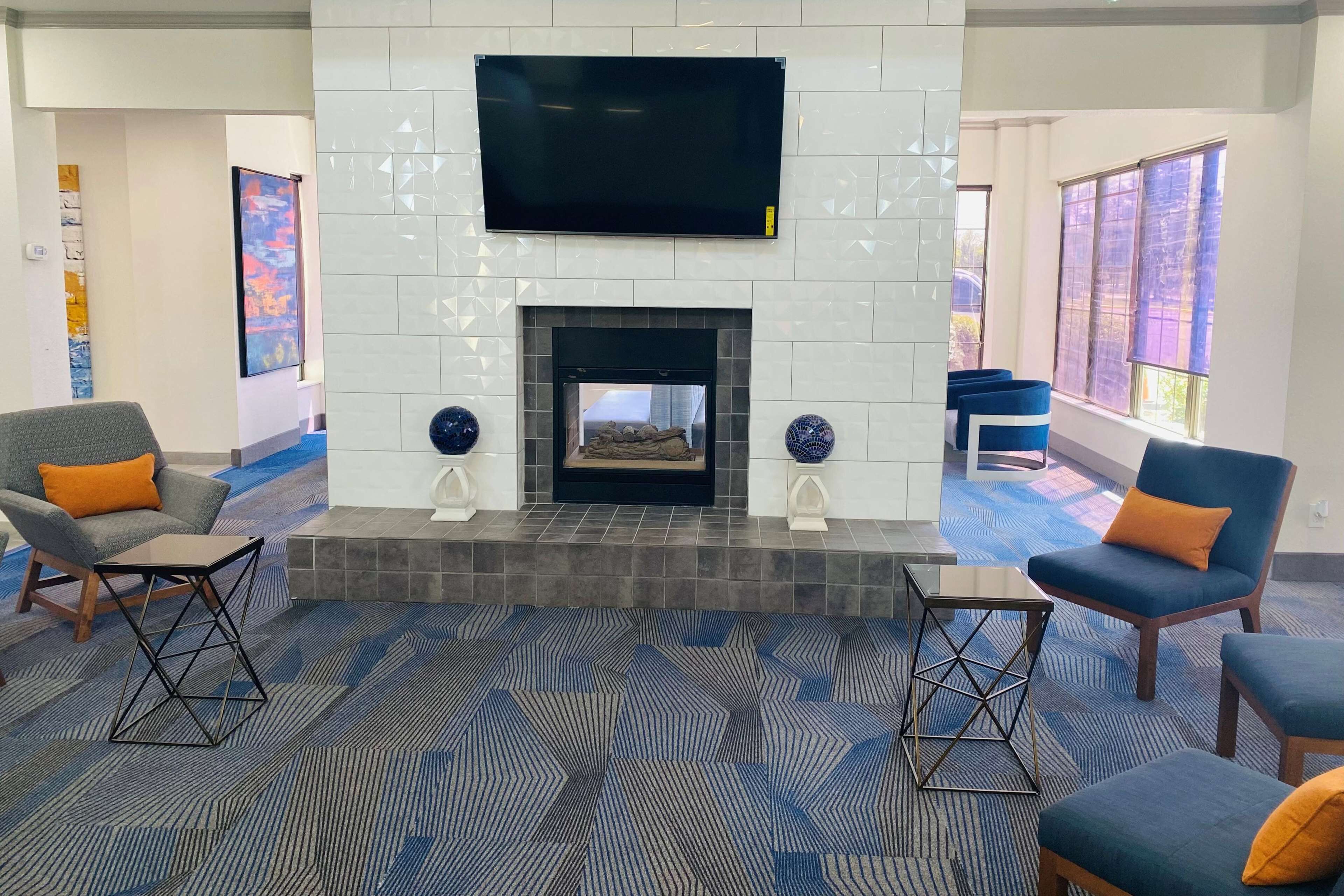 A modern living room with a fireplace, comfortable seating, and large windows.