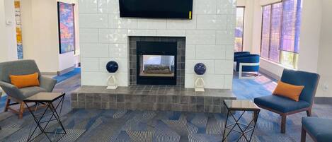 Una sala de estar moderna con chimenea, asientos cómodos y ventanas amplias.