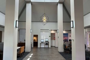Eine geräumige Lobby mit einem modernen Kronleuchter, Sitzbereichen und einer Rezeption.