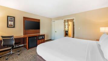 A hotel room with a large bed, a desk with a chair, a television, and a microwave.