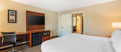 A hotel room with a large bed, a desk with a chair, a television, and a microwave.