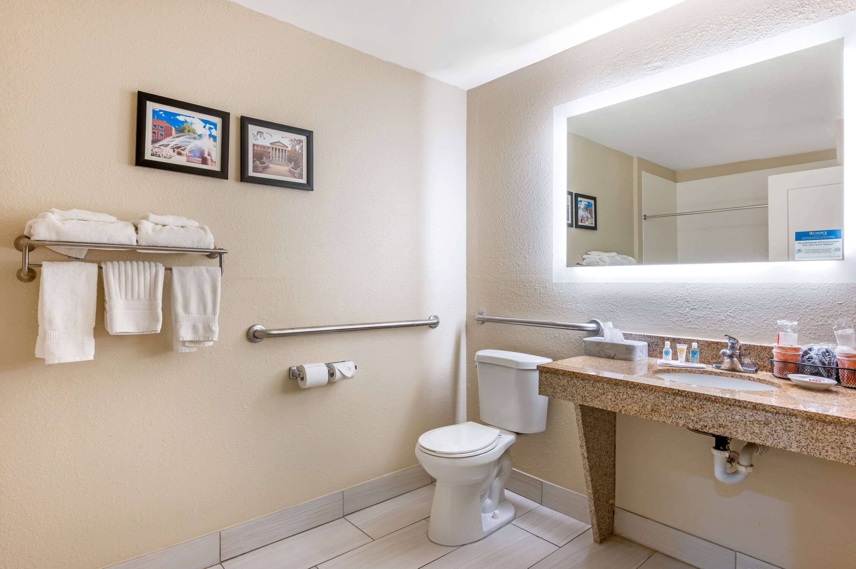 Un bagno con il water, un lavandino, un porta asciugamani e due quadri appesi al muro.