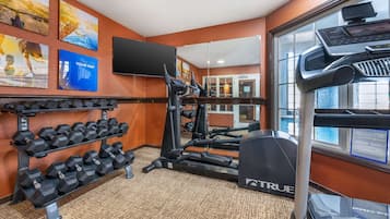 Un gimnasio con cintas de correr, mancuernas y equipo de ejercicio.