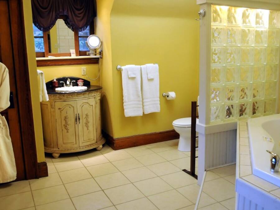 Un baño con bañera, inodoro, tocador y una bata colgada junto a la puerta.