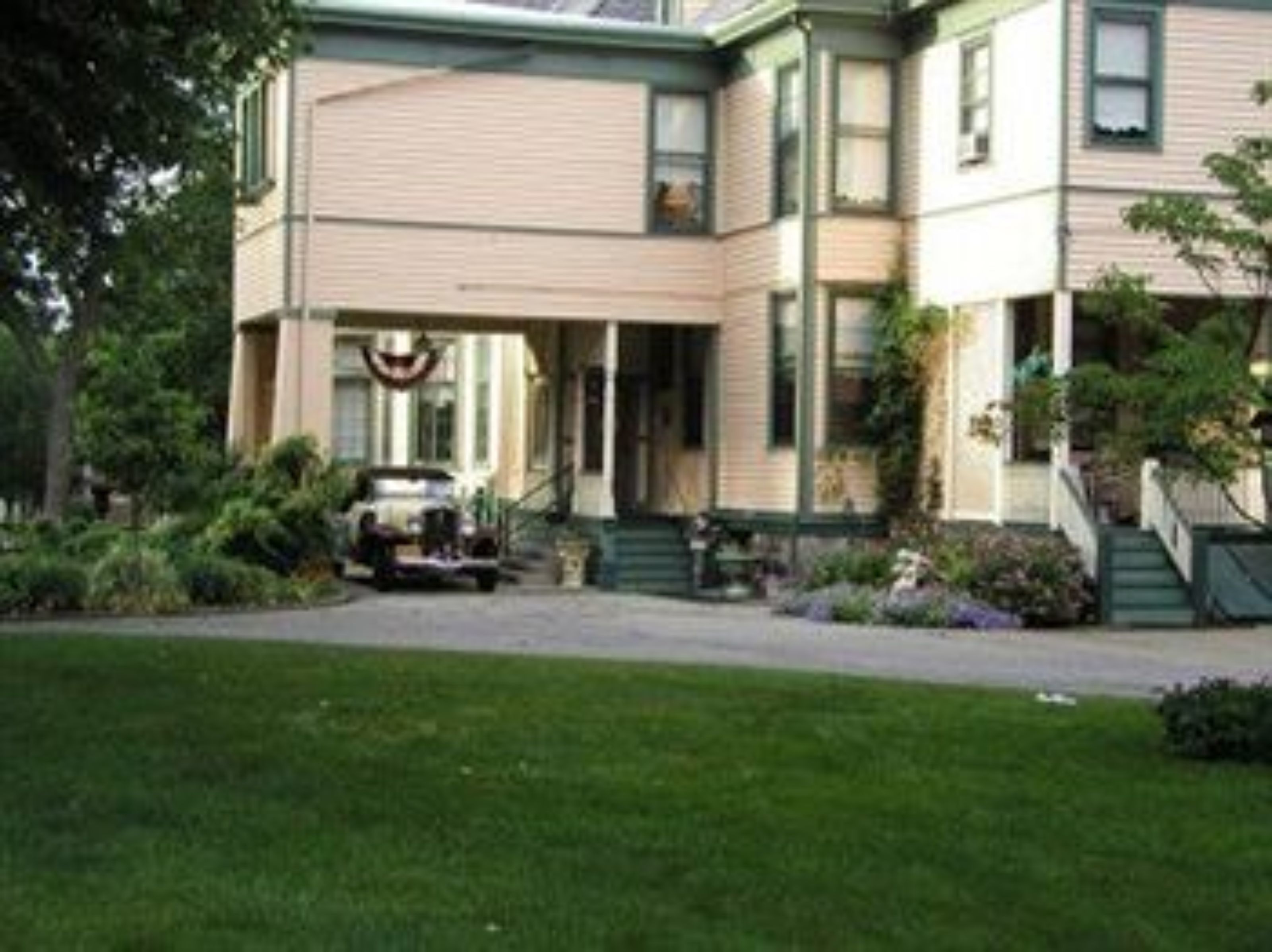 A two-story house with a front porch, a driveway, and a lawn.