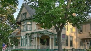 A large, two-story house with a prominent porch and a flag in front.