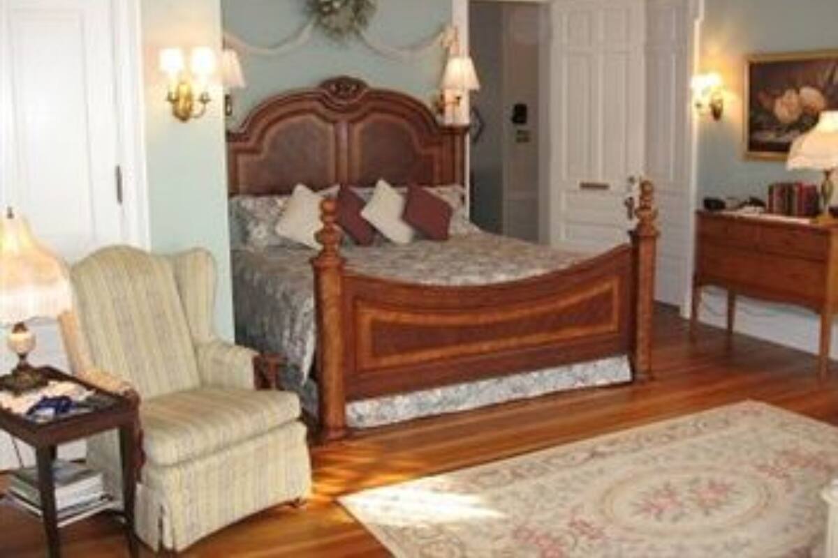 A bedroom with a wooden bed, a chair, a desk, and a rug.