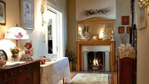 A cozy living room with a fireplace, a table with a lamp, and a decorative mirror.