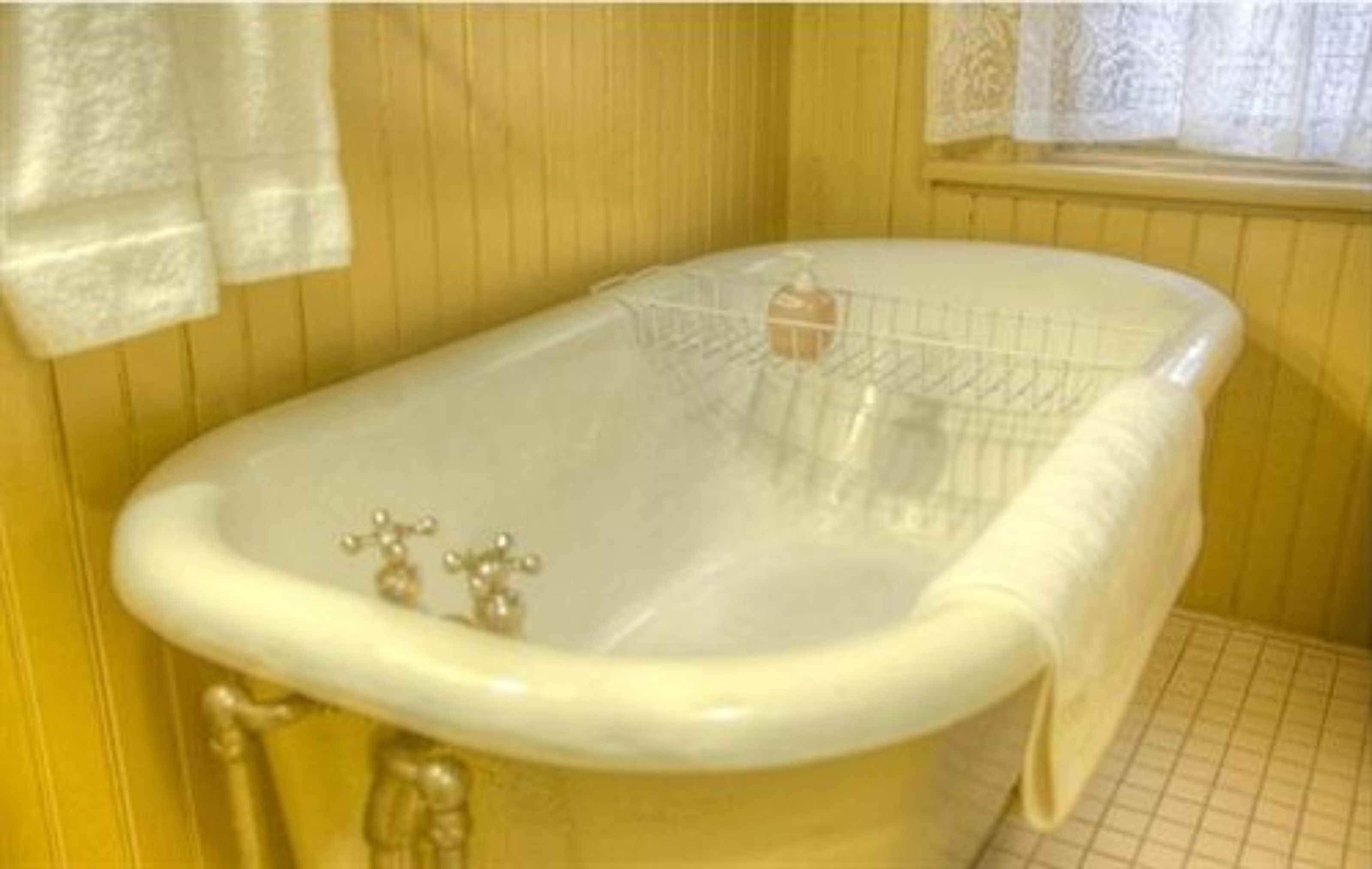 A bathtub with a shower tray, a faucet, and a towel hanging on the wall.