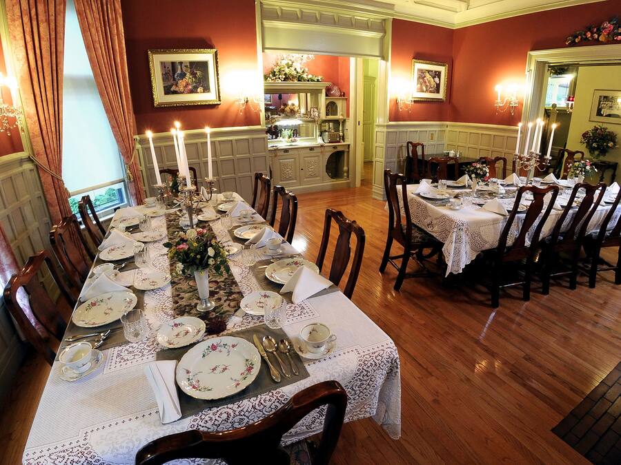 A dining room with a long table set for a meal, surrounded by chairs.