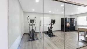 Une salle de sport moderne équipée de machines d’exercice, d’un distributeur automatique et dotée d’un plancher en bois.