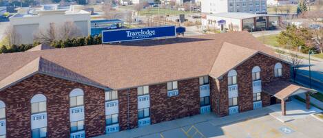A brick building with a sign for Travelodge by Wyndham. It features a parking lot with handicapped parking spaces.