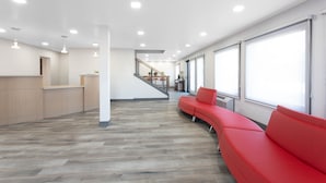 Un hall d’entrée spacieux avec un plancher en bois, un canapé rouge et un escalier menant à un niveau supérieur.