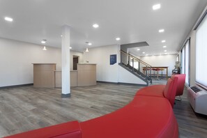 Un hall d’entrée moderne comprenant un comptoir d  ’accueil, un escalier et un espace détente.