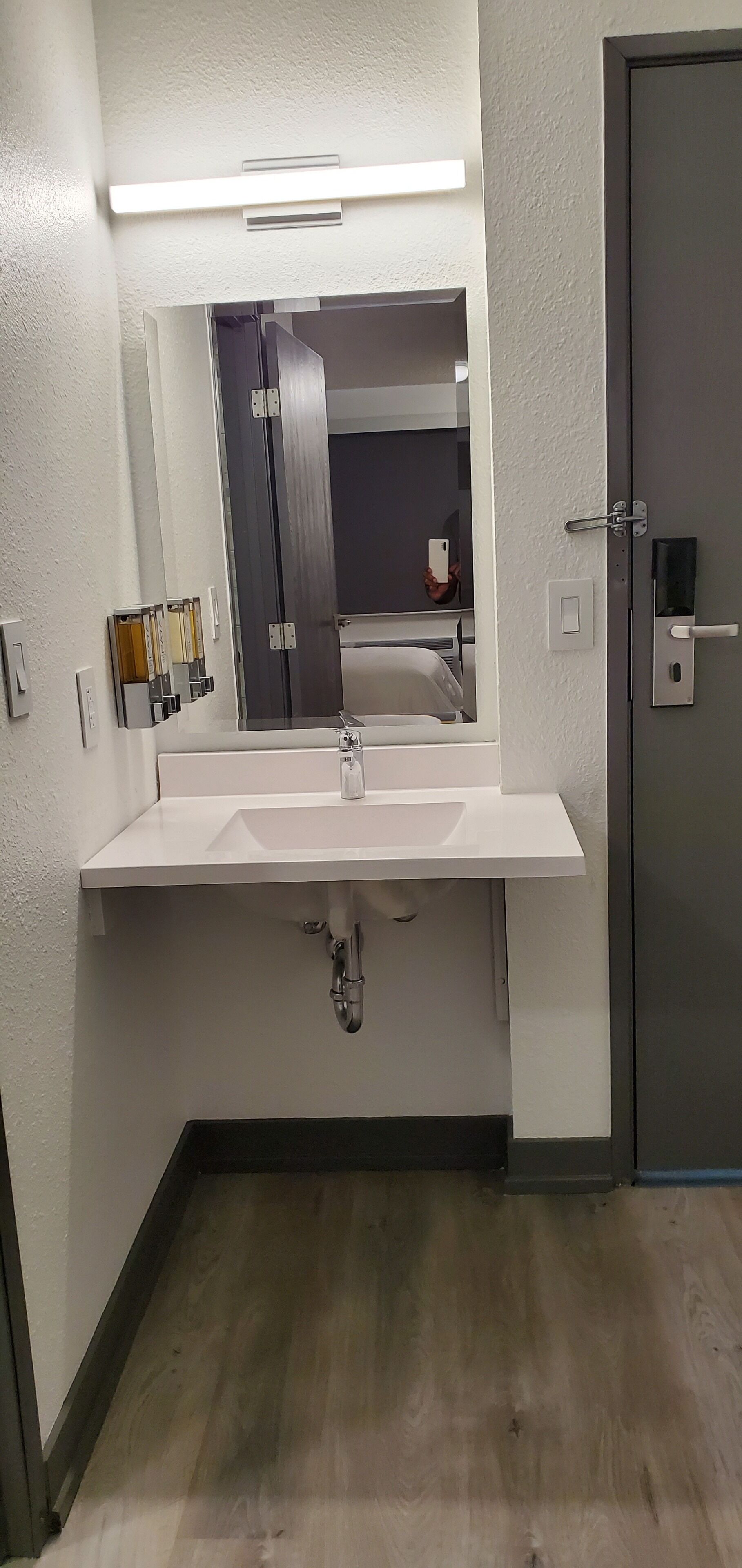A modern bathroom with a white sink, a mirror, and a door with a handle.