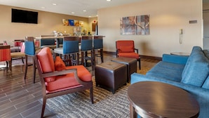 A hotel lobby with a seating area, a kitchen, and a TV mounted on the wall. - Comfort Inn Shelbyville North (Shelbyville)