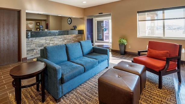 A lobby with a blue sofa, a red chair, a small table, a stone wall, and a reception desk. - Comfort Inn Shelbyville North (Shelbyville)
