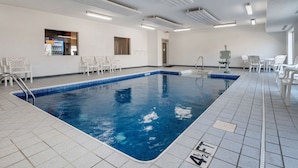 An indoor swimming pool with tiled floors, white chairs, and a vending machine. - Comfort Inn Shelbyville North (Shelbyville)