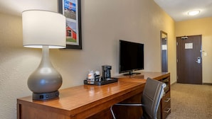 A hotel reception desk with a lamp, a flat-screen TV, a coffee maker, and a chair. - Comfort Inn Shelbyville North (Shelbyville)