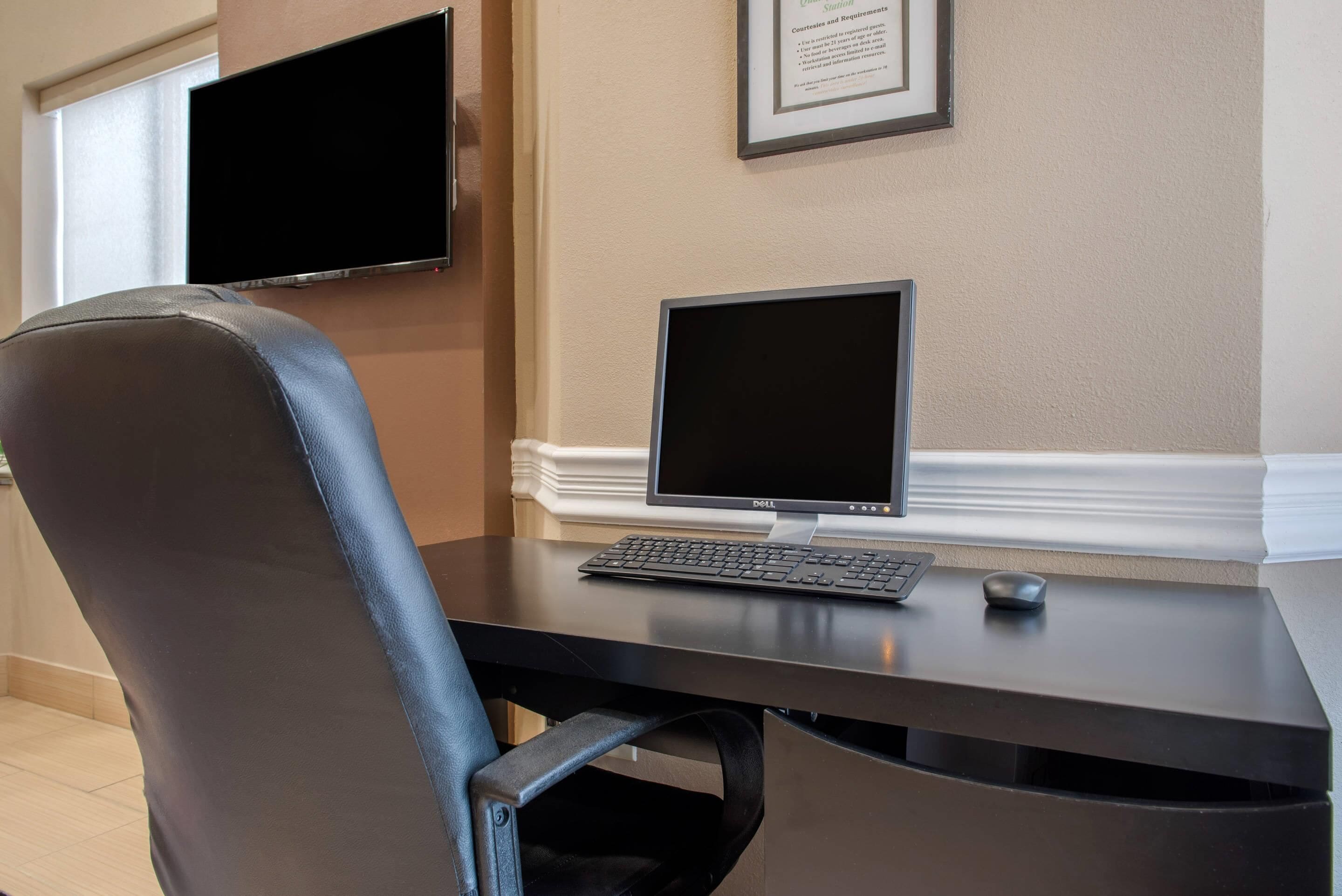 A desk with a computer, a chair, and a framed certificate on the wall.