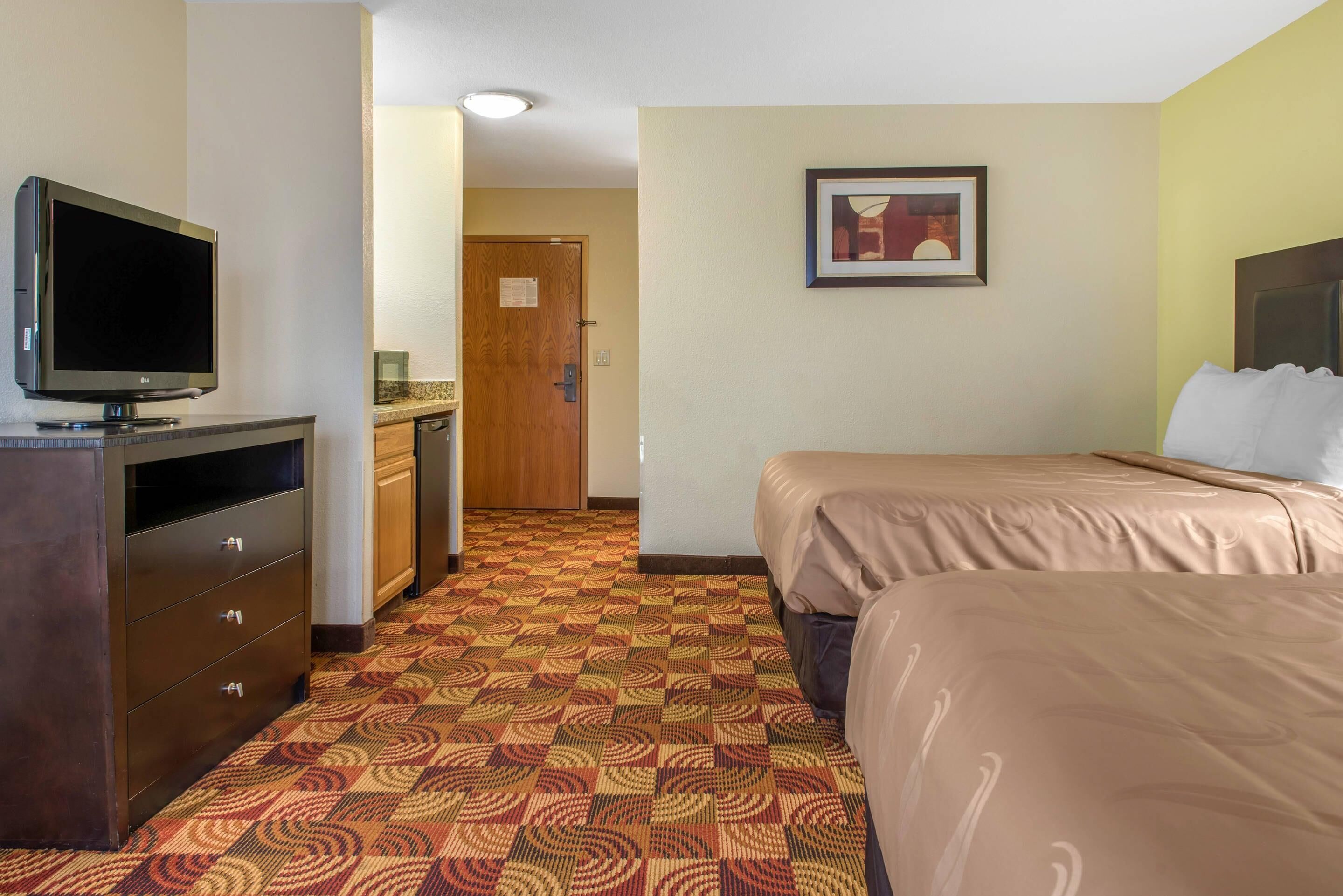 Une chambre d’hôtel équipée d’une télévision, d’un lit, d’un bureau et d’une kitchenette.