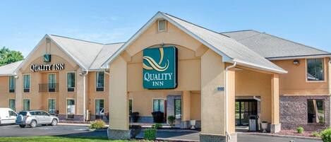 A two-story Quality Inn with a beige exterior and a green sign.