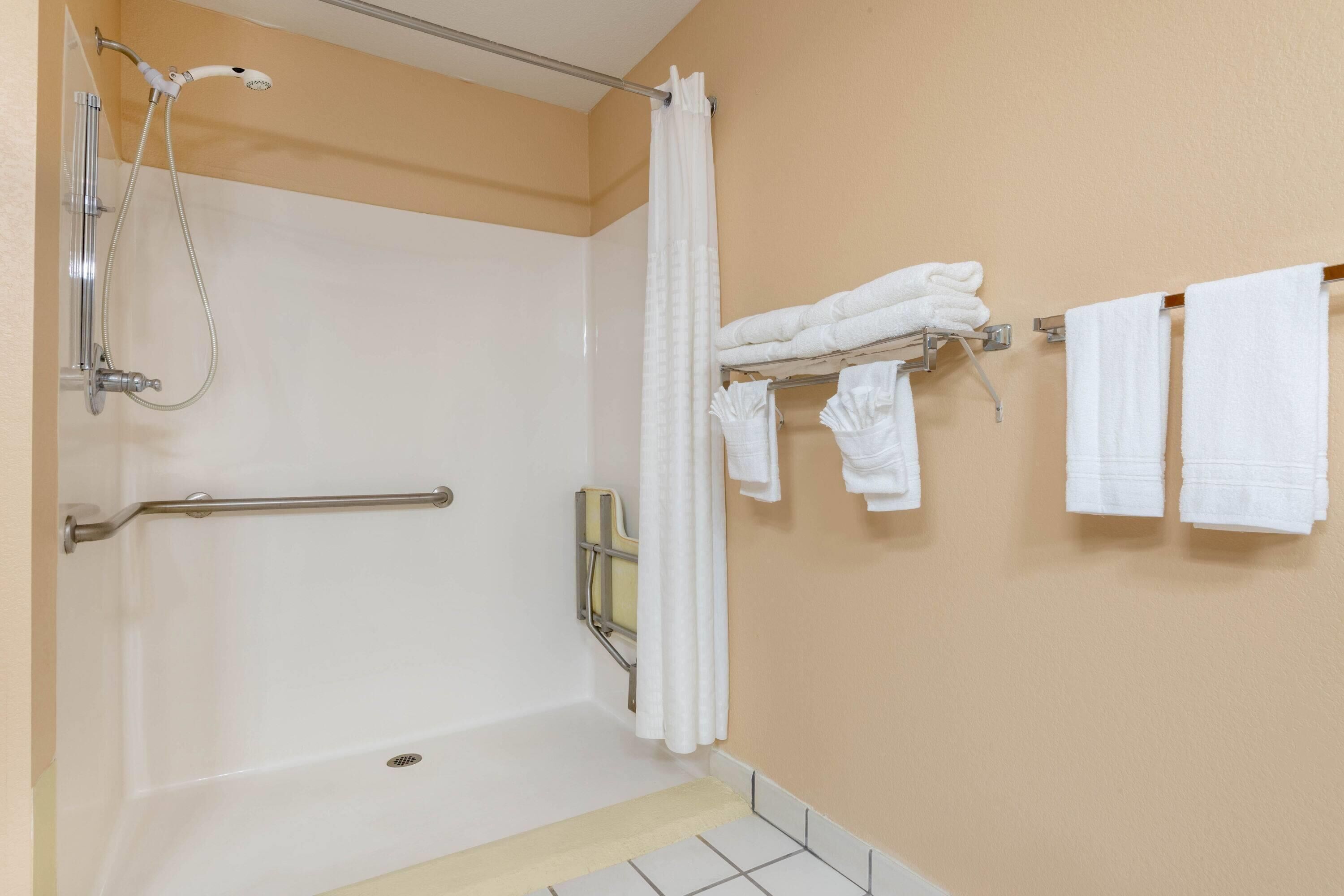 A bathroom with a bathtub, a shower, and a towel rack with towels.