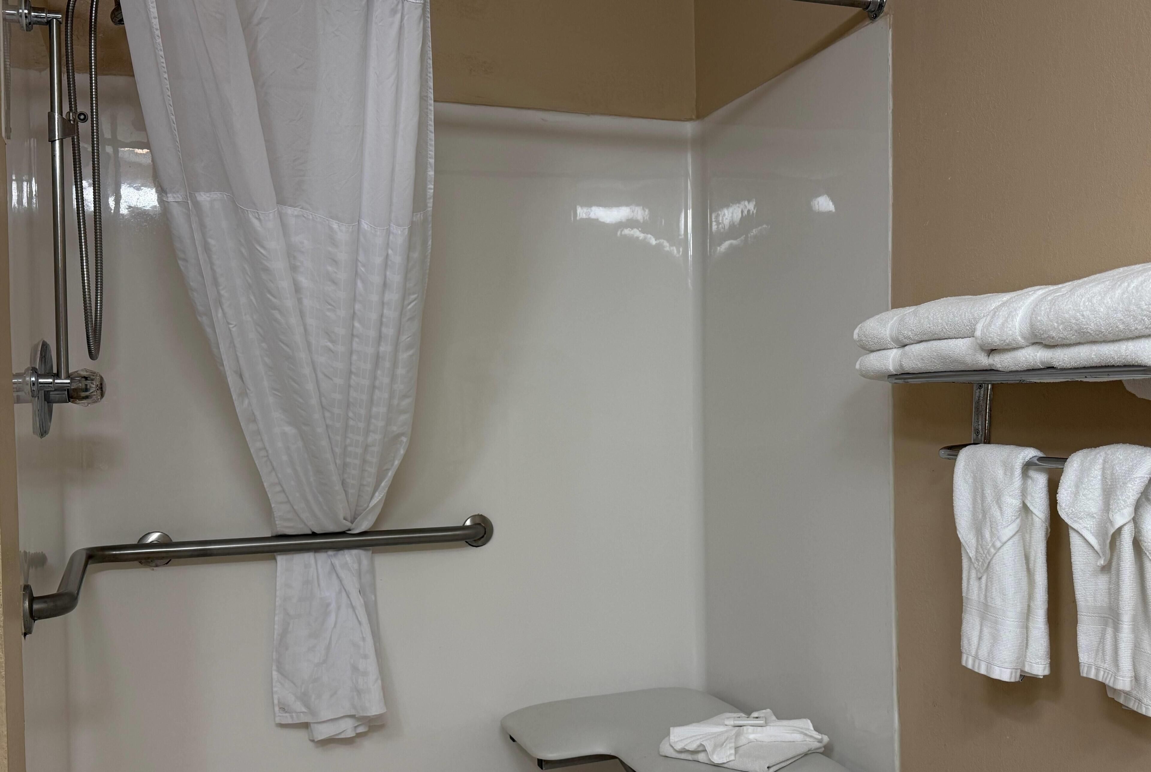A bathroom with a shower, toilet, and a towel rack with towels.