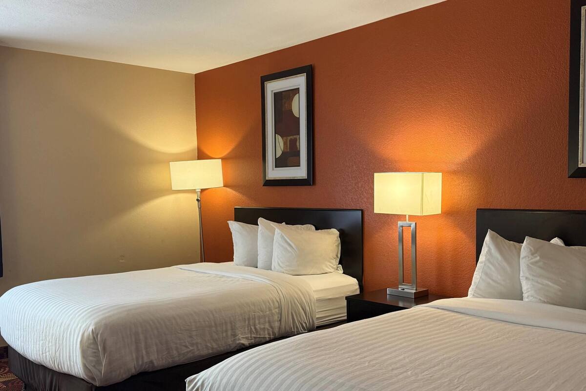 Habitación de hotel con dos camas, un cuadro en la pared y dos lámparas de noche.