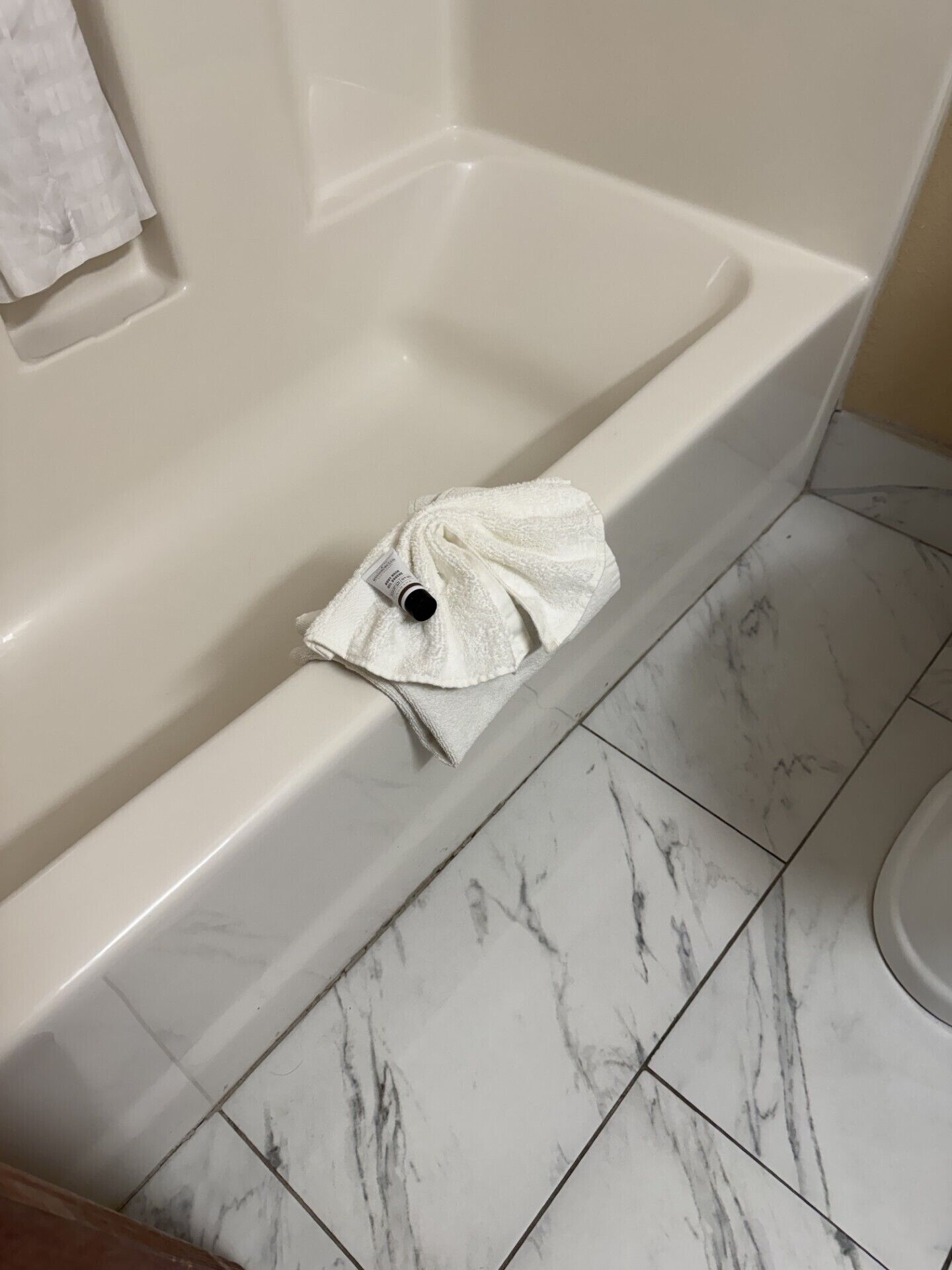 A bathtub with a white towel and a bottle of shampoo.