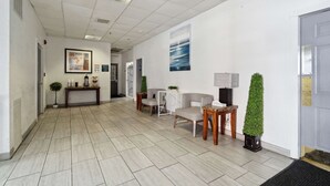 A spacious lobby with a tiled floor, a reception desk, seating area, and a door with a doormat. - Econo Lodge Inn & Suites Waterloo Downtown (Waterloo)