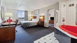 A hotel room with a bed, bedside table, lamp, and a red bathtub. - Econo Lodge Inn & Suites Waterloo Downtown (Waterloo)